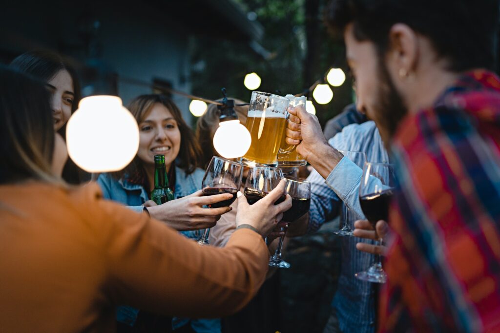 Friends toasting beers and wine at the dusk